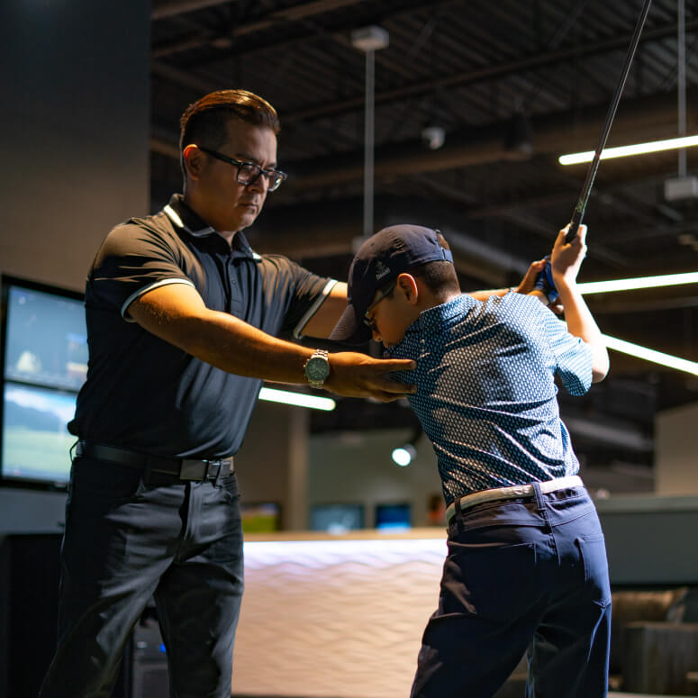 Golf instructor guiding a player’s stance during a lesson at Studio Golf South Bay.