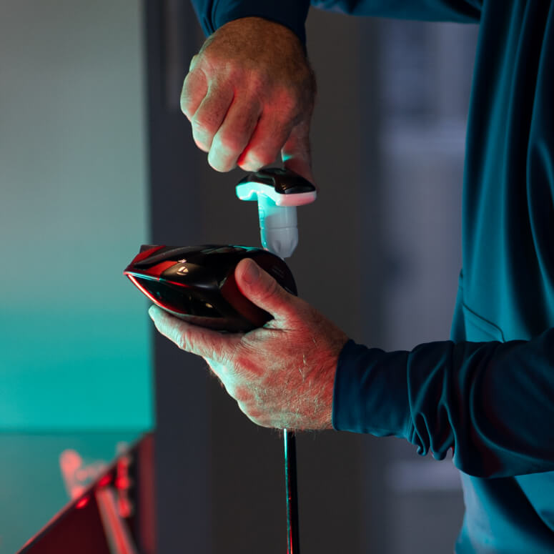 Close-up of a club fitter adjusting a driver head during a custom golf fitting session at Studio Golf South Bay.